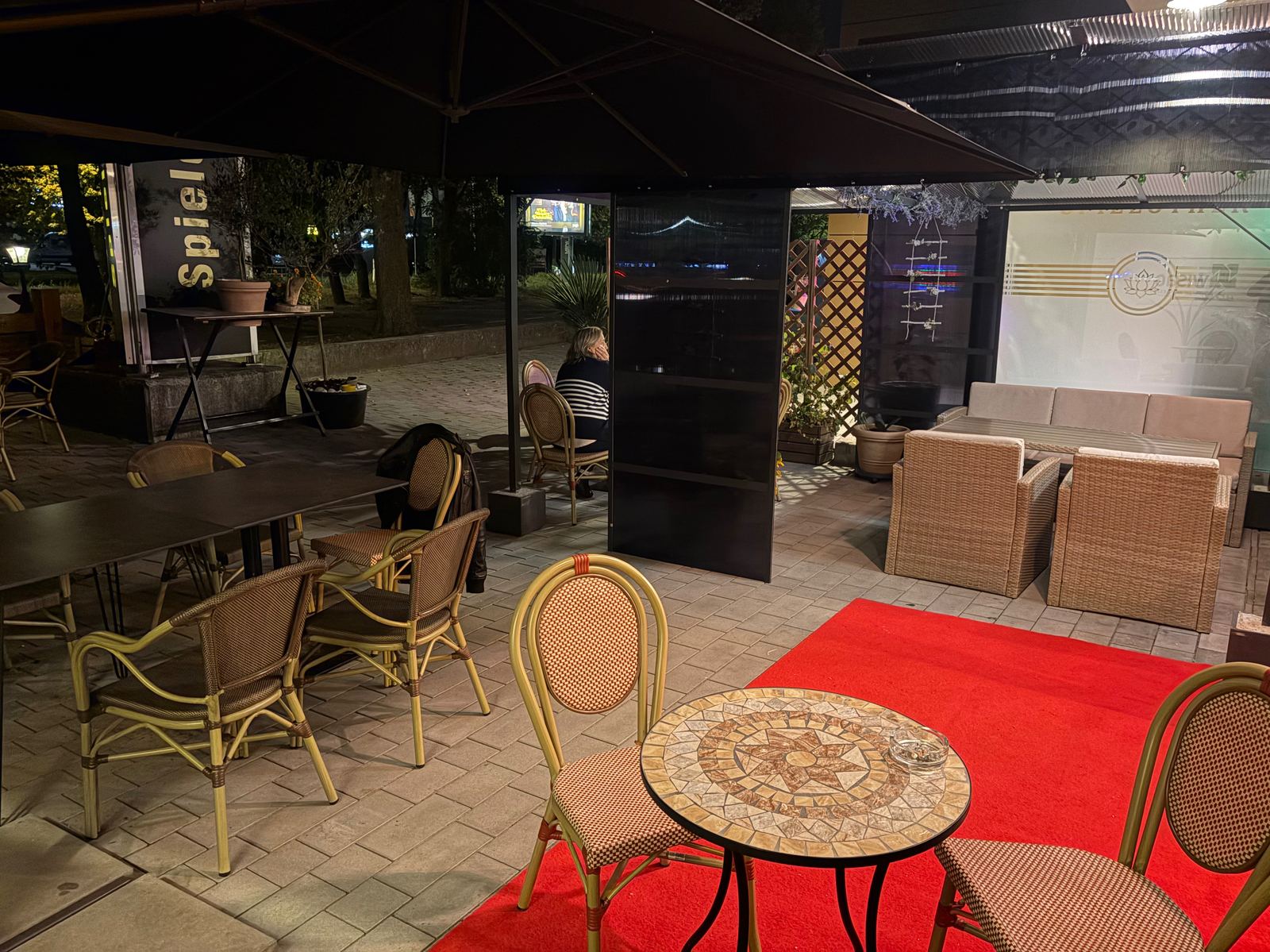 Terrasse am Abend mit Mosaiktisch, Bistrostühlen und Lounge-Ecke