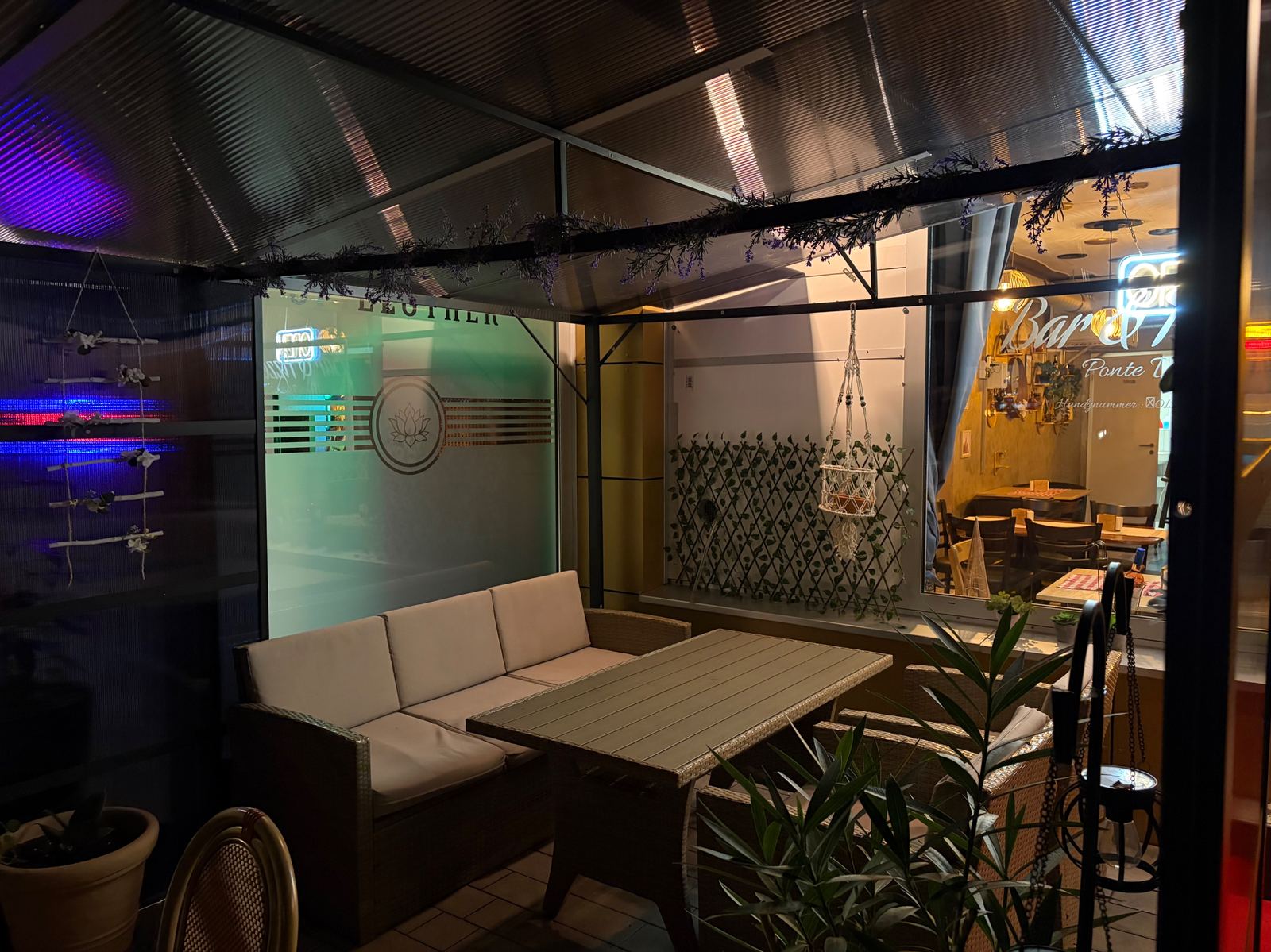 Überdachte Lounge-Ecke mit Sofa auf der Terrasse